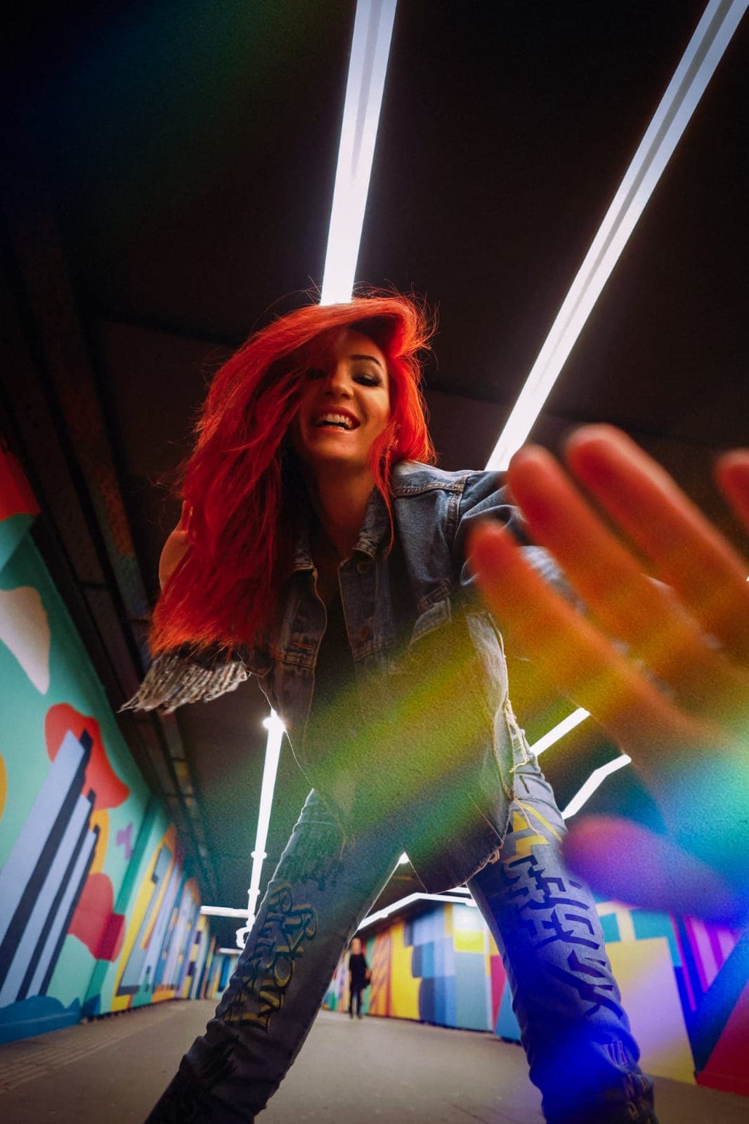 REAVI under linear lights in a colorful passage